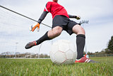 Goalkeeper in red kicking ball away from goal