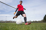 Goalkeeper in red kicking ball away from goal