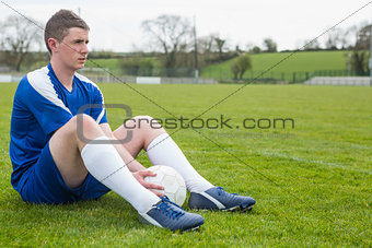 Football player in blue taking a break on the pitch