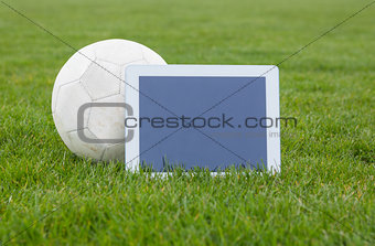 Football and tablet with blank screen on pitch
