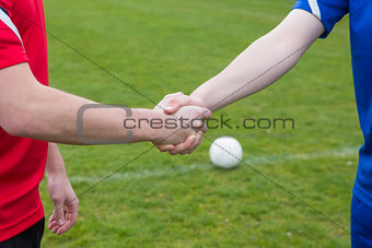Football players in blue and red shaking hands