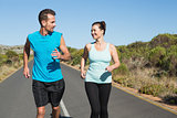 Fit happy couple jogging on the open road together