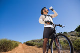 Fit cyclist drinking water on country terrain