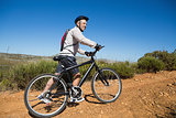 Fit cyclist pushing bike uphill on country terrain