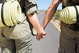 Hitch hiking couple standing holding hands on the road