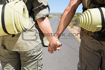 Hitch hiking couple standing holding hands on the road