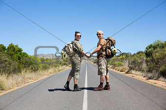 Hitch hiking couple holding hands on the road smiling at camera