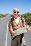 Handsome hiker holding map and smiling at camera