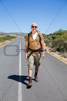 Handsome hiker walking on road and smiling at camera