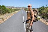 Handsome hiker walking on road and smiling at camera