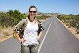 Pretty hiker standing on road and smiling at camera
