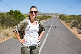 Pretty hiker standing on road and smiling at camera