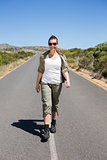 Pretty hiker walking on road and smiling at camera