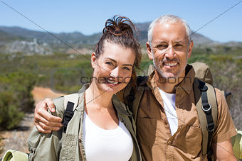 Hiking couple smiling at camera on mountain trail
