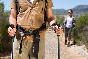 Hiking couple walking on mountain trail with poles