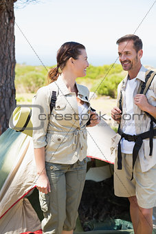 Outdoorsy couple smiling at each other outside their tent