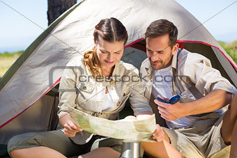 Outdoorsy couple looking at the map outside tent