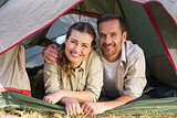 Outdoorsy couple smiling at camera from inside their tent