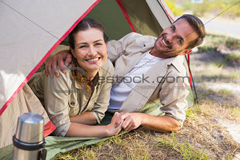 Outdoorsy couple smiling at camera inside their tent