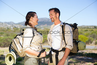 Hiking couple smiling at each other in the countryside