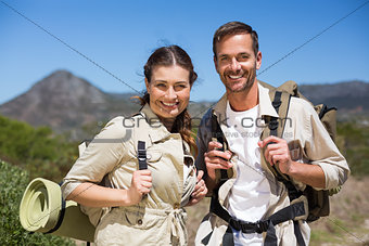Hiking couple standing and smiling at camera on country terrain