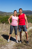 Active couple standing on country terrain smiling at camera