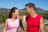 Active couple standing on country terrain smiling at each other