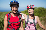 Active couple cycling in the countryside smiling at camera
