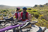 Fit cyclist couple sitting at the summit smiling at each other