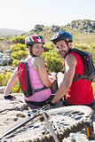 Fit cyclist couple sitting at the summit smiling at camera