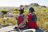 Fit cyclist couple sitting at the summit looking around