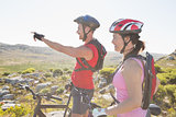 Fit cyclist couple looking ahead on mountain trail