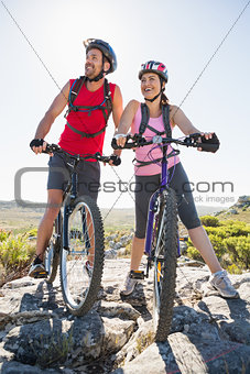 Fit cyclist couple looking ahead on mountain trail