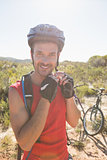 Fit cyclist adjusting helmet strap on country terrain