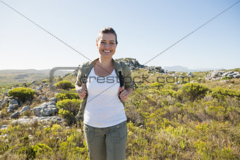 Pretty hiker smiling at camera on mountain terrain