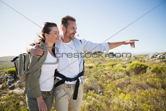 Hiking couple pointing and smiling on country terrain