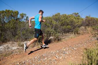 Athletic man jogging up country trail