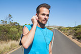 Athletic man adjusting his earphones on a run