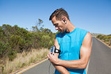 Athletic man adjusting his music player on a run
