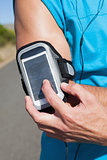 Athletic man adjusting his music player on a run