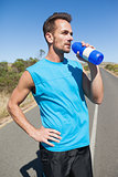 Athletic man on open road taking a drink