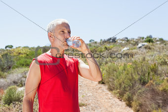 Fit man drinking water on mountain trail