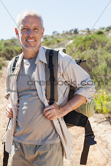 Handsome hiker smiling at camera in the countryside