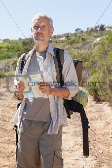 Handsome hiker consulting the map in the countryside