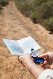 Hiker holding his compass and map in the countryside