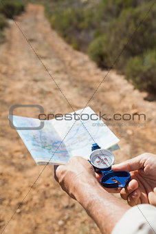 Hiker holding his compass and map in the countryside