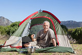 Happy camper holding mug outside his tent