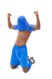 Excited football player in blue cheering on his knees