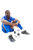 Football player sitting on the ground holding ball
