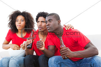 Nervous football fans in red on the sofa
